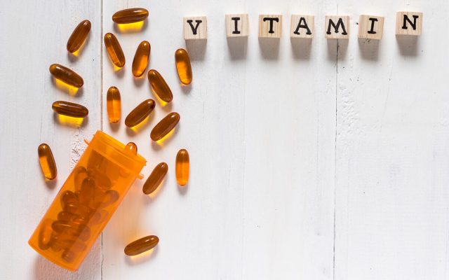 Vitamin D from Fish oil capsules in an orange bottle on white wooden background, supplemental and healthcare product, flat lay surface